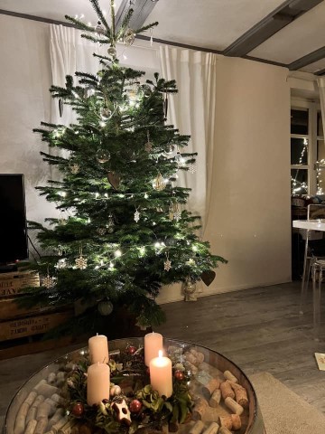 Lumières blanches et bougies de l’Avent au premier plan. — Sapin Nordmann naturel